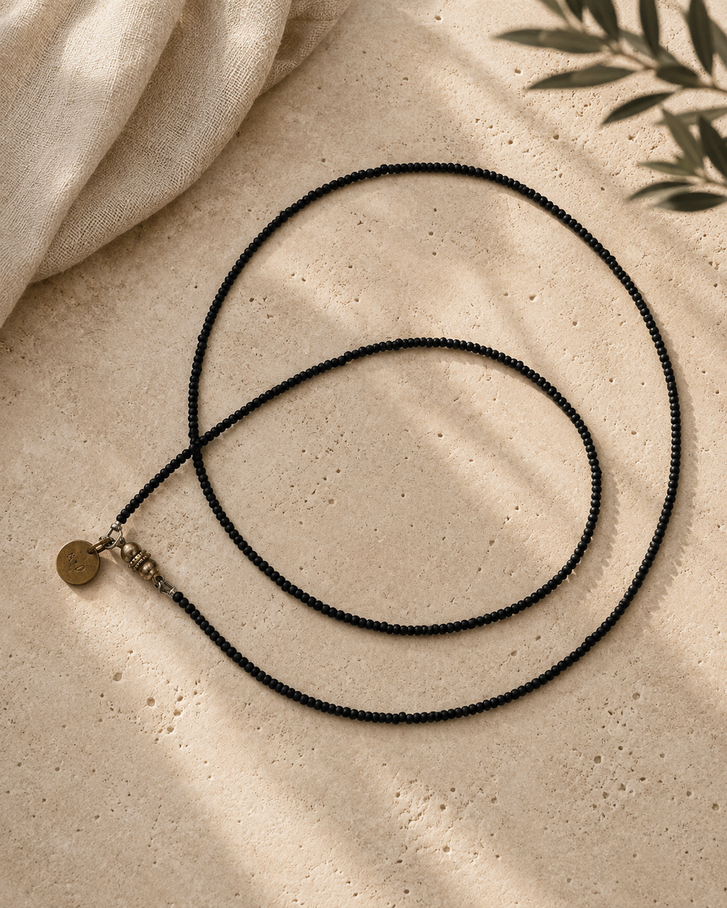 Lange ketting met matte zwarte glaskraaltjes in verschillende groottes en zilverkleurige accenten.