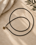 Lange ketting met matte zwarte glaskraaltjes in verschillende groottes en zilverkleurige accenten.