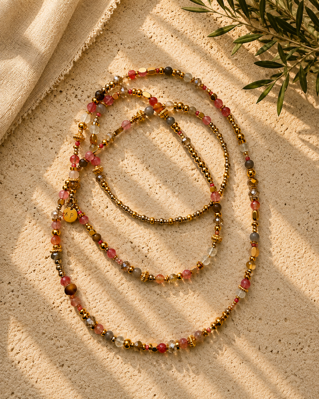 Lange ketting met natuursteentjes en glaskralen in zachte roze- en champagnetinten en goudkleurige metalen accenten.