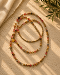Lange ketting met natuursteentjes en glaskralen in zachte roze- en champagnetinten en goudkleurige metalen accenten.