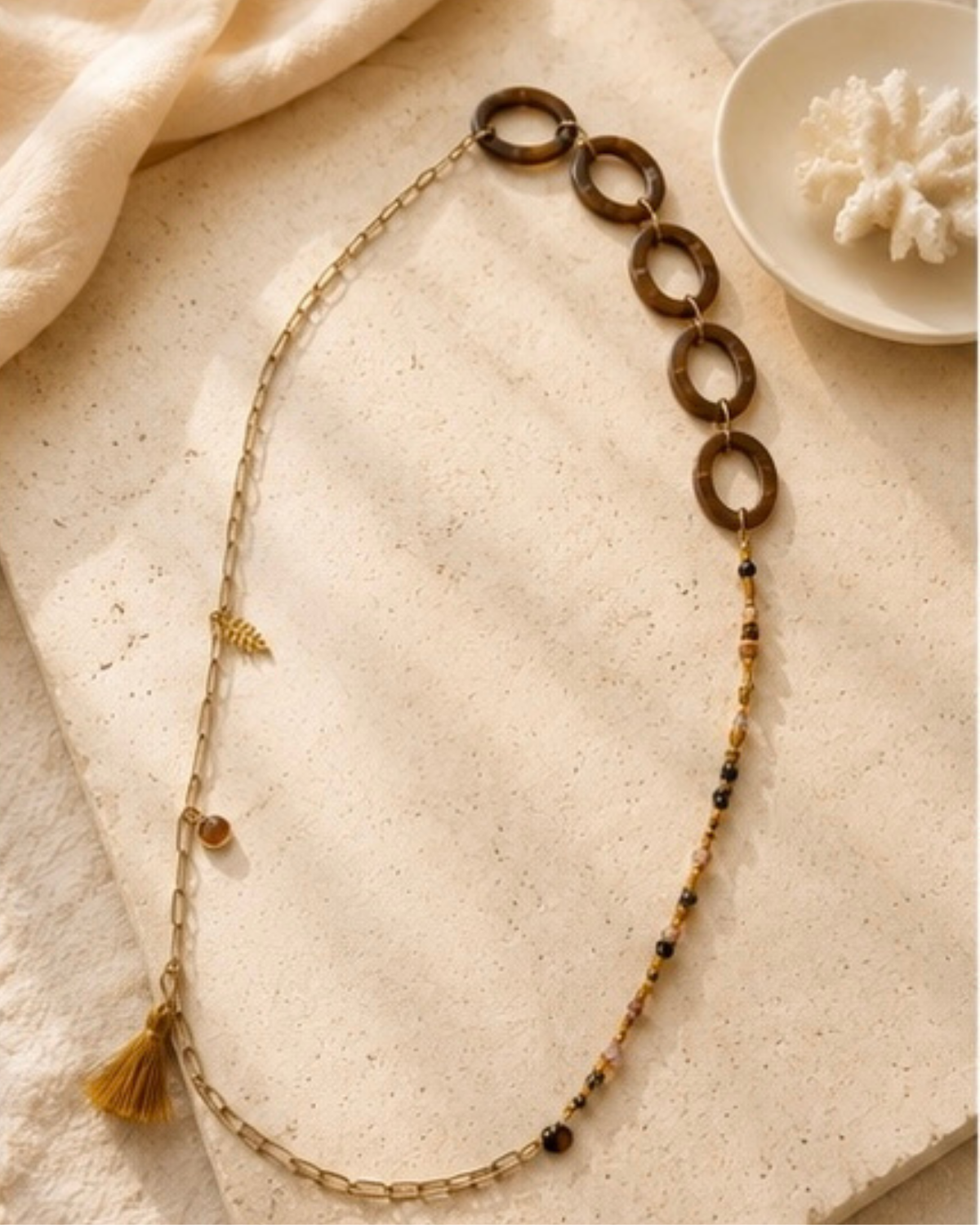 Lange ketting met natuursteentjes gecombineerd met ovale acrylringen en metalen details in goud- en bruintinten