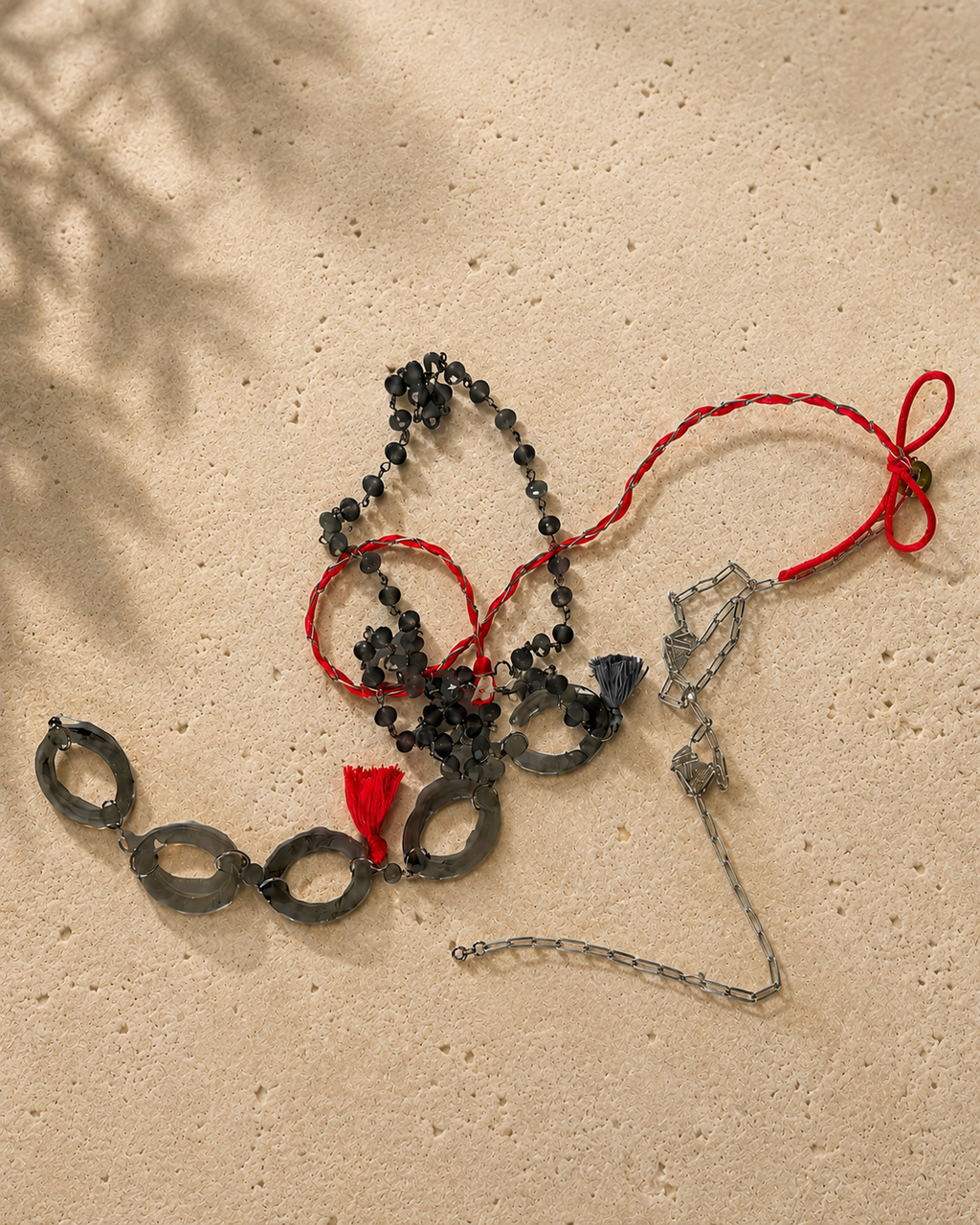 Zeer lange ketting met grijze facetgeslepen natuursteentjes, ovale kunststof schakels, zilverkleurige metalen elementen en neonroze details van satijn.