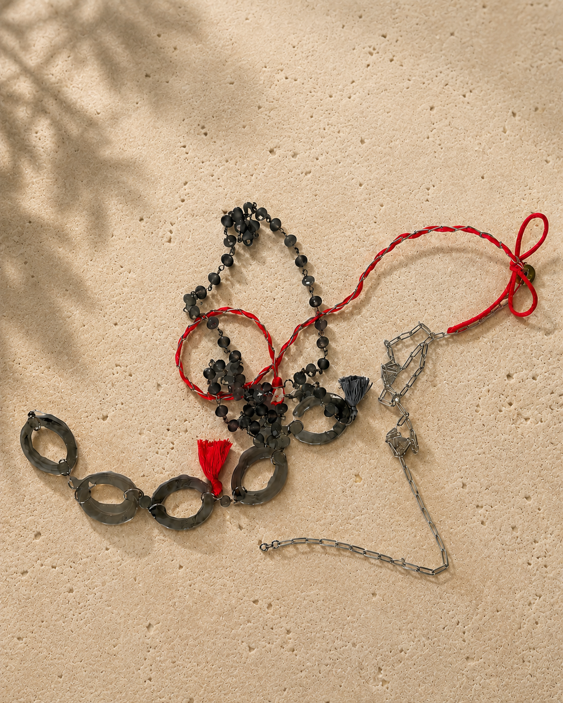 Zeer lange ketting met grijze facetgeslepen natuursteentjes, ovale kunststof schakels, zilverkleurige metalen elementen en neonroze details van satijn.