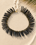 Ketting met langwerpige zwarte kokoskralen, afgewisseld met kleine warmgele glaskraaltjes.