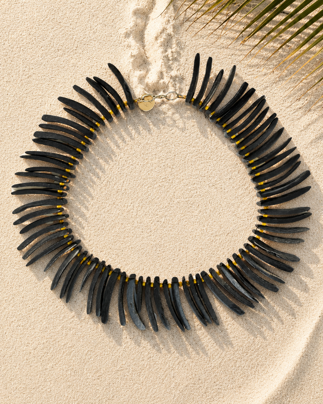 Ketting met langwerpige zwarte kokoskralen, afgewisseld met kleine warmgele glaskraaltjes.